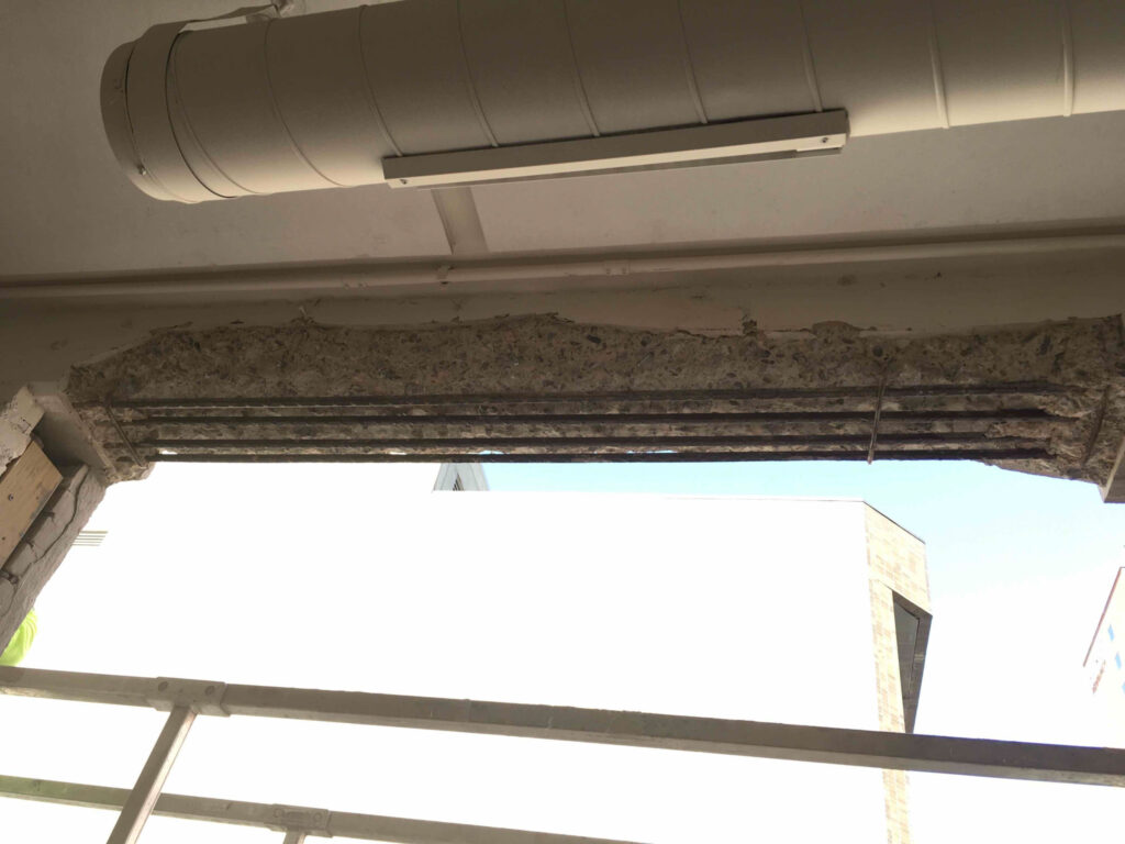 exposed rebar on crumbling concrete window beam at Tire Discounters Home Office