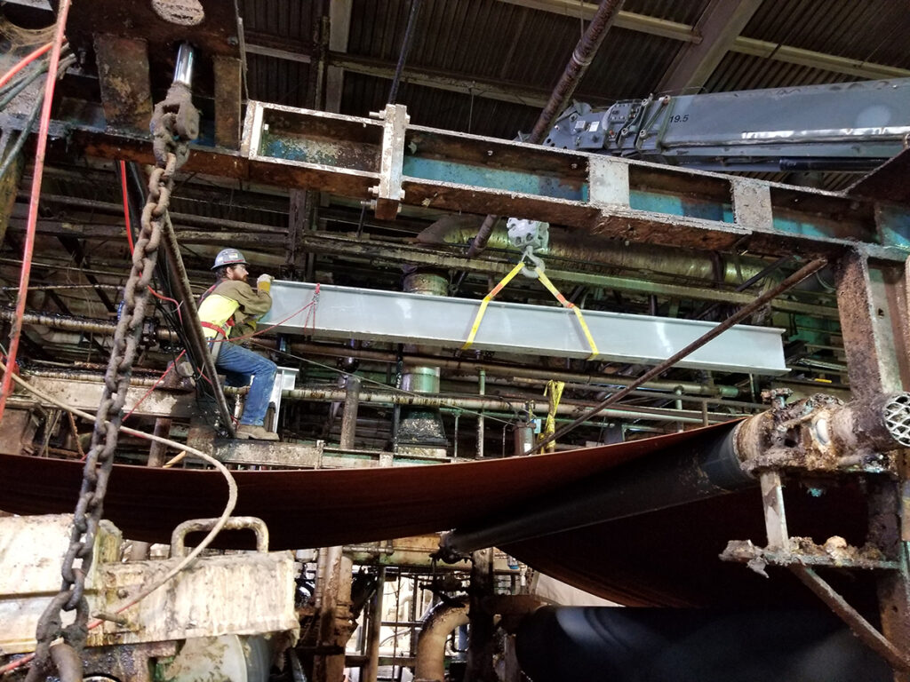 worked carefully maneuvers steel beam over active machinery as part of Cincinnati Paperboard repairs